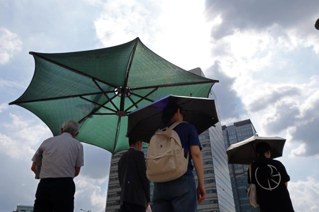 People walk under the blazing sun in central Seoul on July 23 2025 Yonhap