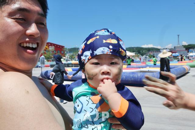 2025년 7월 28일 충남 보령에서 열린 머드축제에서 한 아이의 볼에 머드를 바르고있다
