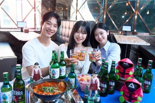 방학 시즌을 맞은 대학생들이 ‘테라·참이슬 오징어 게임 에디션’ 제품과 굿즈를 함께 즐기고 있다 사진하이트진로 