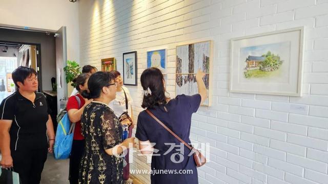 중국 베이징 798 예술특구 Gallery FingerPrint갤러리지문에서 열린 2025 아주글로벌 아트페어 전시회에서 현지 작가들이 작품을 감상하고 있다사진아주글로벌교류협회