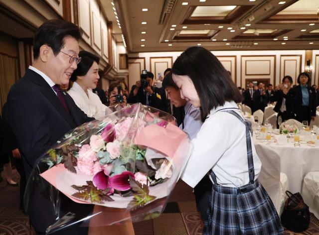 President Lee Jae Myung and First Lady Kim Hea Kyung receive a bouquet from a Korean resident during a luncheon meeting with the Korean diaspora community at a Tokyo hotel on August 23 2025 Yonhap