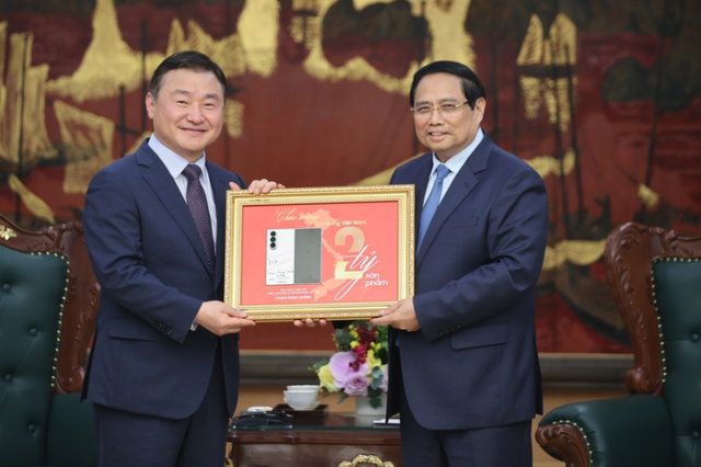 Thủ tướng Việt Nam Phạm Minh Chính phải và Quyền Giám đốc kiêm Trưởng Bộ phận Trải nghiệm Thiết bị DX của Samsung Electronics Roh Tae-moon chụp ảnh kỷ niệm tại Trụ sở Chính phủ Hà Nội vào ngày 26 trong khi cầm tấm biển kỷ niệm thành tựu sản xuất 2 tỷ điện thoại di động của Samsung Electronics Việt Nam ẢnhSamsung Việt Nam
