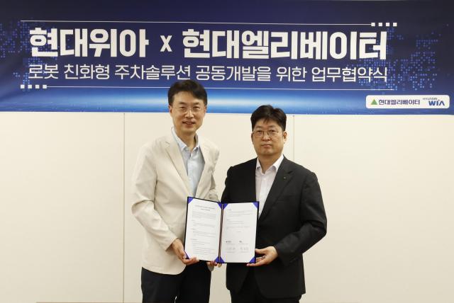 현대위아 모빌리티솔루션사업부 백익진 상무왼쪽와 현대엘리베이터 승강기사업본부장 이원해 상무가 28일 경기도 의왕시 현대위아 의왕연구소에서 열린 ‘로봇 친화형 주차솔루션 공동개발을 위한 업무협약식’에서 기념 사진을 찍고 있다 현대위아 제공
