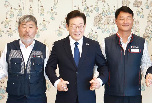 이재명 대통령이 4일 서울 용산 대통령실 청사에서 열린 양대노총 위원장과의 오찬 간담회에 참석해 김동명 한국노총 위원장왼쪽 양경수 민주노총 위원장과 기념촬영을 하며 손을 잡고 있다사진연합뉴스