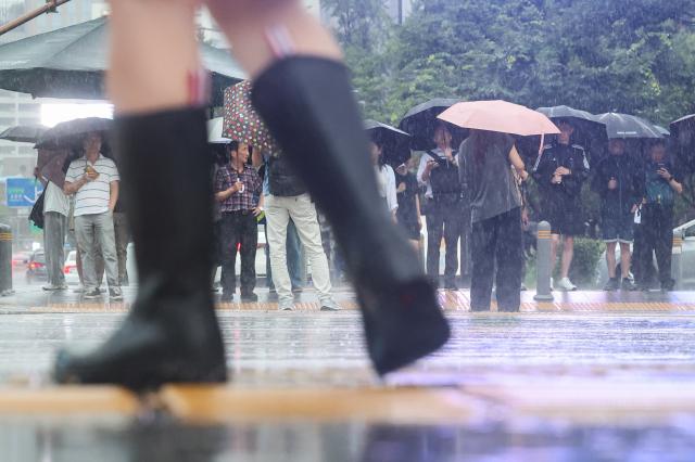 비가 내린 지난달 13일 서울 종로구 광화문 네거리에서 장화를 신거나 우산을 쓴 시민들이 길을 건너기 위해 신호를 기다리고 있다 사진연합뉴스