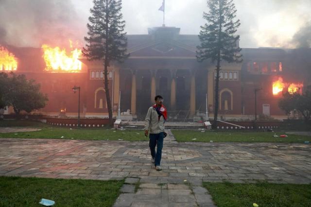 A man walks in front of a burning parliament building during protests in Kathmandu Nepal AFP-Yonhap