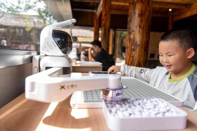 A boy plays go with an AI-powered robot at a tourist site in Congjiang county southwest Chinas Guizhou province Aug 9 2025 Peoples Daily