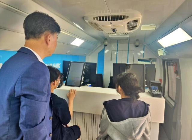 지난 18일 충북 청주 수곡중학교에서 열린 금융체험교실에 참여한 학생들이 우리은행 이동점포 위버스WeBUS를 통해 은행 업무를 간접 체험하고 있는 모습 사진우리은행
