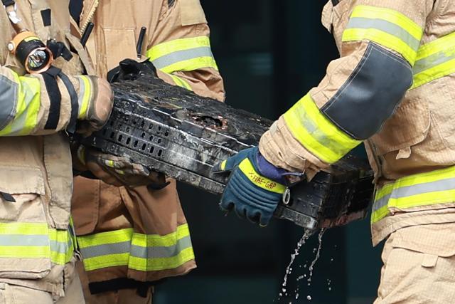 Firefighters move a burnt lithium-ion battery at the National Information Resources Service in Yuseong-gu Daejeon Sept 27 Yonhap