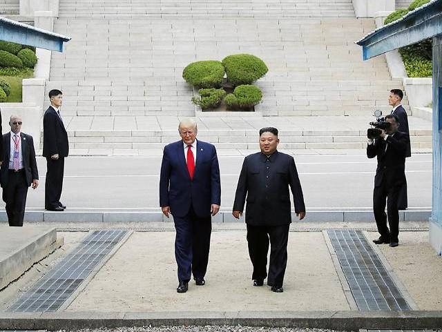 US President Donald Trump and North Korean leader Kim Jong-un walk together across the military demarcation line at Panmunjom in June 2019 YONHAP