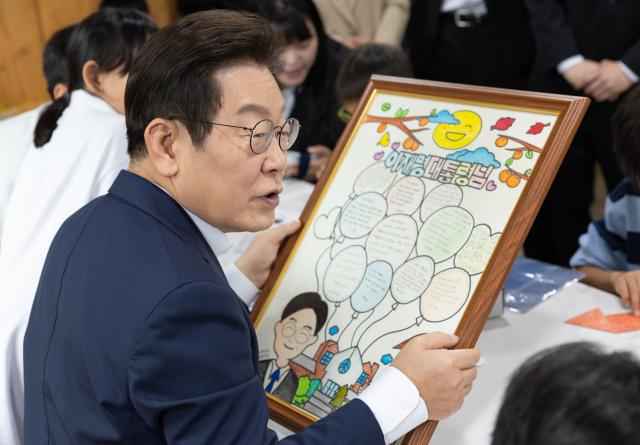 이재명 대통령이 추석 연휴 첫날인 3일 인천의 한 아동양육시설을 방문해 어린이들이 준비한 메시지가 적힌 액자를 살펴보고 있다 사진대통령실