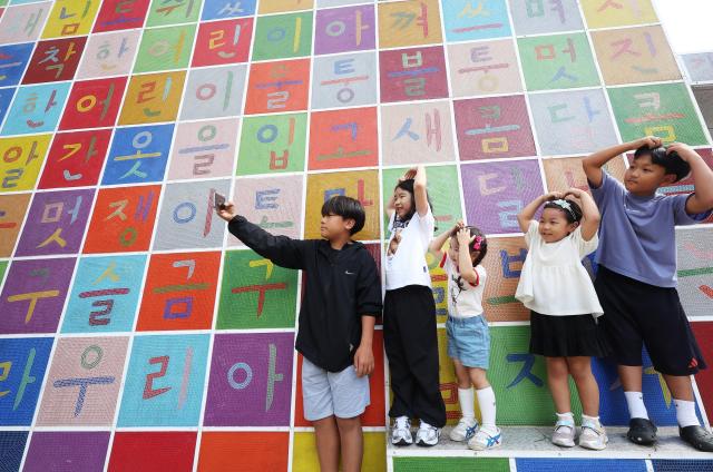 Children take photos in front of a Hangul-themed mural at the Gyeonggi Childrens Museum in Yongin Gyeonggi Province on Oct 8 2025 a day before Hangul Day YONHAP