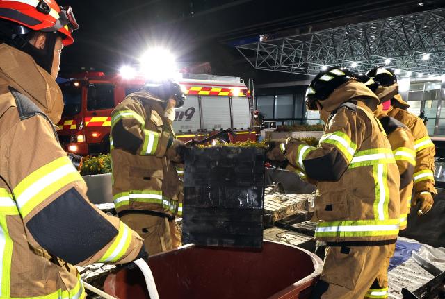 Firefighters move scorched lithium-ion batteries into a water tank at the National Information Resources Service in Yuseong District Daejeon on the night of Sept 27 2025 Yonhap