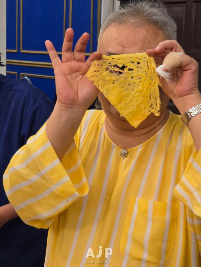 Chef Dato Ismail Ahmad tries hiding his face with a slice of roti jala a Malaysian crepe-like snack at Restoran Rebung Chef Ismail in Kuala Lumpur Oct 3 2025 AJP Kim Dong-young
