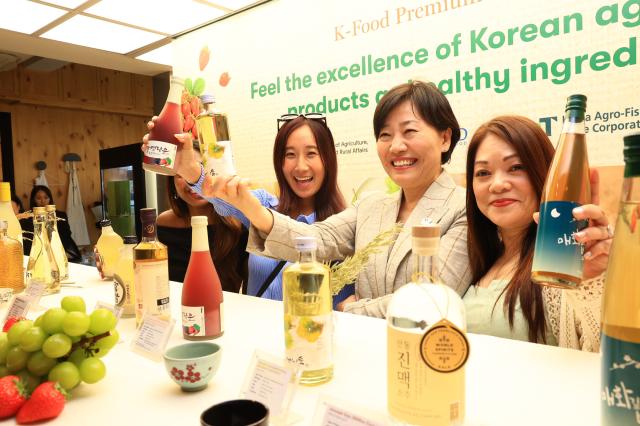 송미령 농림축산식품부 장관이 지난 3월 싱가포르에서 퓨전 외식업체를 방문 전통주를 소개하며 기념 촬영하고 있다사진농림축산식품부