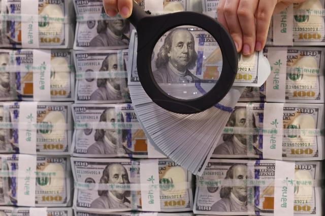 서울 중구 소재 하나은행 위변조대응센터에서 직원이 미국 달러를 들어 보이고 있는 모습 사진연합뉴스