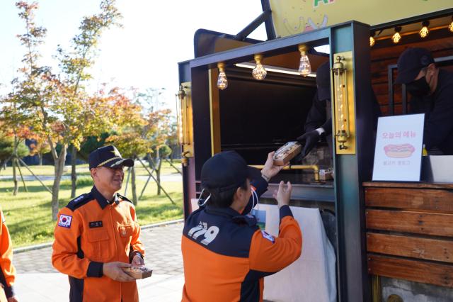 경북소방본부 소방관들이 한국원자력환경공단이 진행한 APEC 성공 개최 응원 캠페인에서 핫도그를 수령하고 있다 사진한국원자력환경공단
