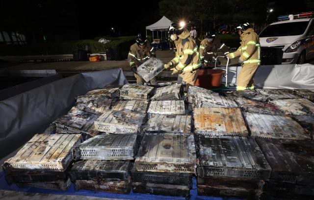 Firefighters move burnt lithium-ion batteries at the scene of a fire at the National Information Resources Service in Yuseong-gu Daejeon on the night of Sept 27 Yonhap