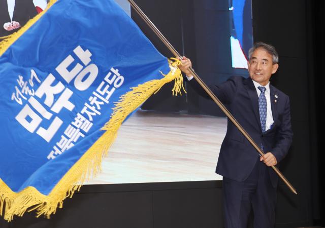 2일 전북 전주시 완산구 전주대학교 JJ아트홀에서 열린 더불어민주당 전북특별자치도당 임시당원대회에서 신임 도당위원장으로 선출된 윤준병 의원이 도당기를 흔들고 있다