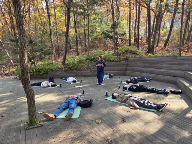 해설사의 안내에 따라 눈을 감고 자연의 소리를 듣는 사운드 워킹 체험 참가자들 사진GKL 사회공헌재단