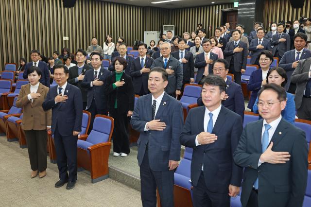 더불어민주당 정청래 대표 김병기 원내대표를 비롯한 의원들이 27일 서울 여의도 국회에서 열린 의원총회에서 국기에 경례를 하고 있다사진연합뉴스