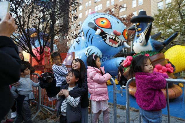 메이시스 추수감사절 퍼레이드를 하루 앞둔 26일현지시간 뉴욕 맨해튼 어퍼웨스트사이드에서 어린이들이 케이팝 데몬 헌터스 더피 캐릭터 풍선 앞에서 기념사진을 찍고 있다 사진로이터연합뉴스