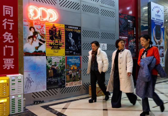 중국 여성들이 베이징에서 일본 음악가 오스미 토시오를 포함한 콘서트 포스터가 부착된 음악 클럽 입구를 지나고 있다 사진로이터·연합뉴스