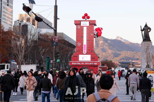 People pass by the “Love Thermometer” donation tower set up at Gwanghwamun Square in Seoul’s Jongno District on the afternoon of Dec 1