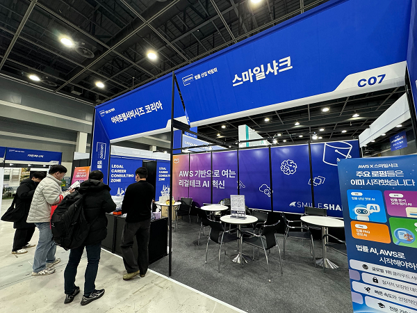 대한민국 법률산업 박람회 2025 스마일샤크와 AWS 공동 부스에서 스마일샤크 직원이 방문객에게 AI 도입 서비스를 소개하고 있다 사진스마일샤크 제공