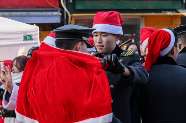 24일 서울 서대문구 연세로에서 열린 ‘2025 사랑의 몰래산타 대작전’ 출정식에서 한 자원봉사자가 동료 봉사자의 망토를 매주고 있다 AJP Yoo Na-hyun