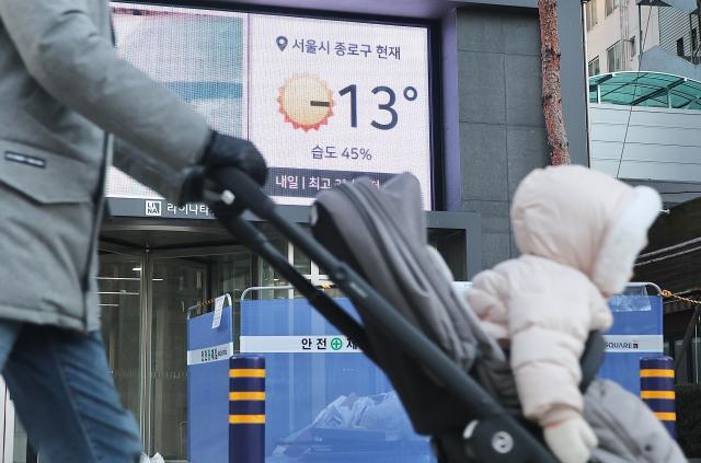 A person pushing a stroller passes by a display showing -13°C 86 degrees Fahrenheit at near Jonggak station in Seoul Dec 26 2025 AJP Han Jun-gu