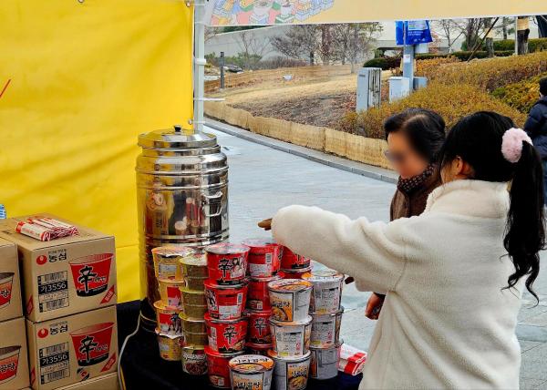 2025 K-푸드 스페셜 페스타 룰렛 이벤트에 당첨된 한 참가자가 농심 라면 제품을 수령하고 있다 사진홍승완 기자