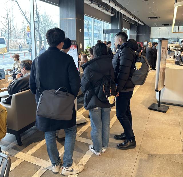 A staff member assists several customers with using kiosks at a cafe in central Seoul on Dec 29 2025 AJP Kim Hee-su
