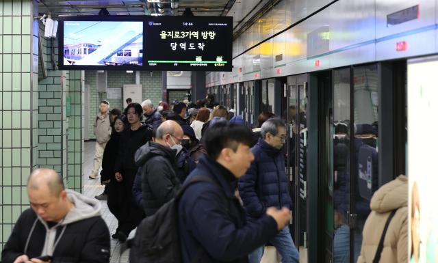 Commuters board a subway train at Euljiro 4-ga Station in Jung District central Seoul on Dec 30