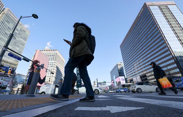 Commuters cross a crosswalk at Gwanghwamun Intersection in central Seoul on the first working day of the new year Jan 2
