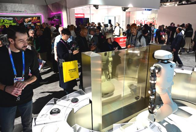 Visitors experience LG Electronics’ home robot “LG Cloi” and its actuator brand “LG Actuator Axiom” at CES 2026 in Las Vegas on Jan 6 showcasing proactive home-care capabilities such as laundry assistance and towel organization 