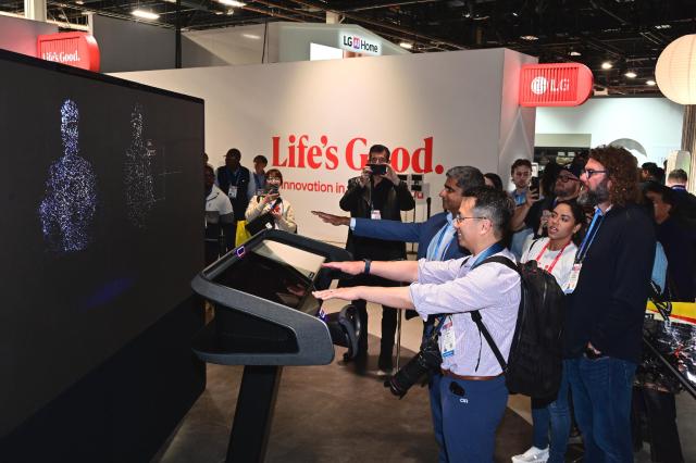 Visitors try out LG Electronics’ AI-powered in-car solutions at CES 2026 where the system analyzes passengers’ gaze to display relevant ads on windows and shows location-based photos tied to personal memories 