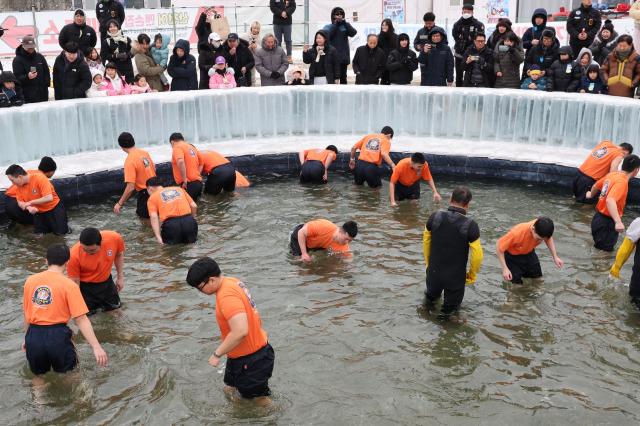 Participants catch mountain trout with their bare hands in icy water at the Hwacheon Sancheoneo Ice Festival in Hwacheon Gangwon Province Jan 12 2026 AJP Han Jun-gu