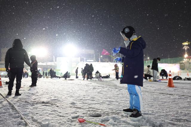 A child tries ice fishing at night at the Hwacheon Sancheoneo Ice Festival in Hwacheon Gangwon Province Jan 12 2026 AJP Han Jun-gu