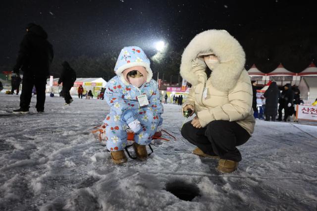 Visitors try ice fishing at night at the Hwacheon Sancheoneo Ice Festival in Hwacheon Gangwon Province Jan 12 2026 AJP Han Jun-gu
