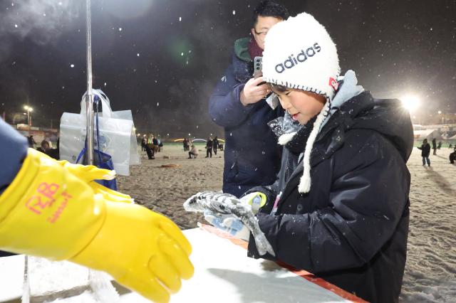 A visitor measures a caught mountain trout at the measuring station at night at the Hwacheon Sancheoneo Ice Festival in Hwacheon Gangwon Province Jan 12 2026 AJP Han Jun-gu