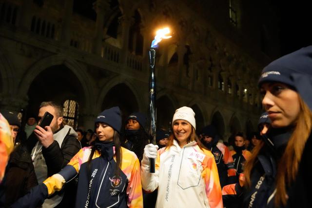 A torchbearer holds an Olympic torch flame in Venice Italy Thursday Jan 22 2026 and its journey will conclude in Milan on February 6 for the Winter Olympics opening ceremony AP Yonhap