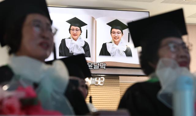Adult graduates watch AI-generated images depicting their childhood during the 2025 Neulpureum School elementary and middle school graduation ceremony at the annex building of Yeongdeungpo District Office in Seoul on Jan 28 2026 Yonhap