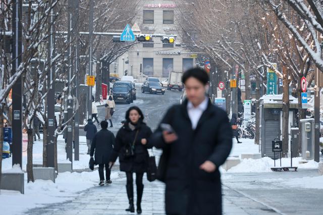 Commuters walk near Gwanghwamun in Seoul on Feb 2 as snow that fell overnight remains on the ground AJP Yoo Na-hyun