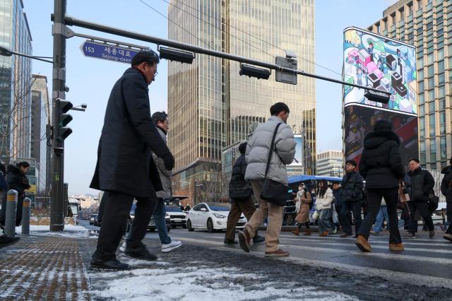 Commuters walk near Gwanghwamun in Seoul on Feb 2 as snow that fell overnight remains on the ground AJP Yoo Na-hyun