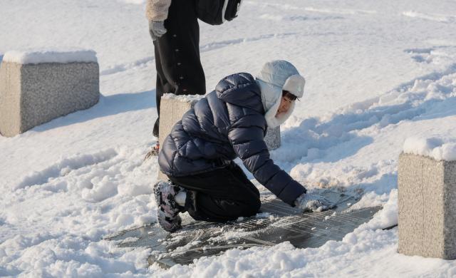 A tourist touches snow near Gyeongbokgung in Seoul as snow that fell overnight remains on the ground on Feb 2 2026 AJP Yoo Na-hyun