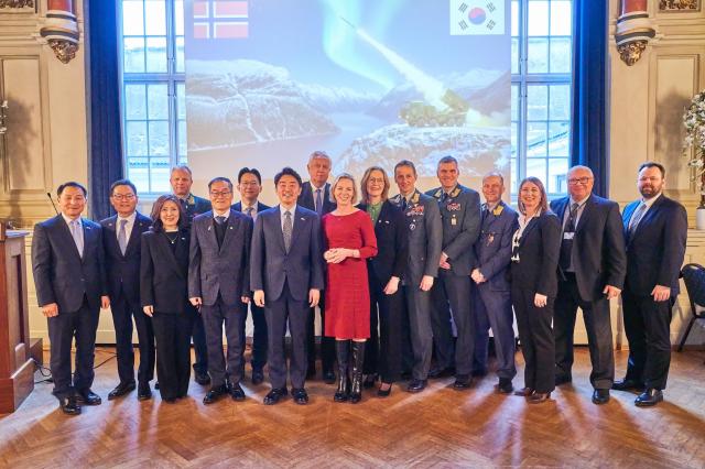 Kang Hoon-sik South Korea’s presidential chief of staff fifth from left and Marte Gerhardsen Norway’s deputy minister of defence red dress pose for a photo following the signing of a contract to supply the Chunmoo multiple rocket launcher on Jan 30 2026 Courtesy of Hanwha Aerospace