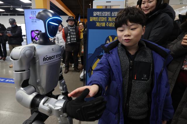 A robot offers a handshake to a child at Koreas first retail robot store at E-mart in Yeongdeungpo Seoul Feb 2 2026 AJP Han Jun-gu