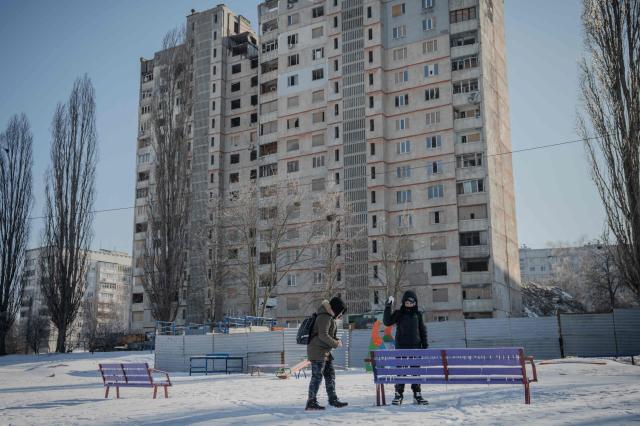 Children play in the snow in front of damaged residential buildings in Kharkiv on Feb 4 2026 amid the Russian invasion of Ukraine AFP-Yonhap  