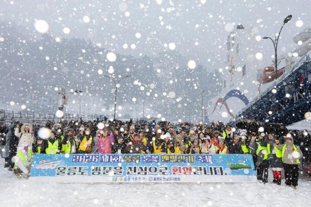 폭설 속에서 진행된 ‘2026 제1회 울릉 눈꽃 맨발걷기 축제’ 참가자들이 사동항에서 기념 촬영을 하고 있다사진울릉크루즈
